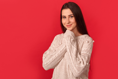 Freestyle. Young woman standing isolated on red hands together smiling cute side viewの写真素材