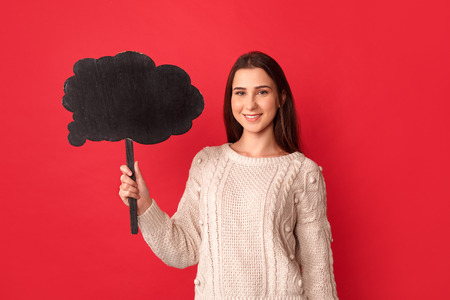 Freestyle. Young woman standing isolated on red with cloud looking camera cheerfulの写真素材