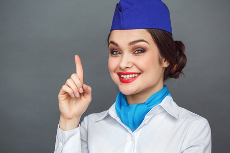 Professional Occupation. Stewardess standing isolated on grey pointing up idea smiling toothy close-upの写真素材