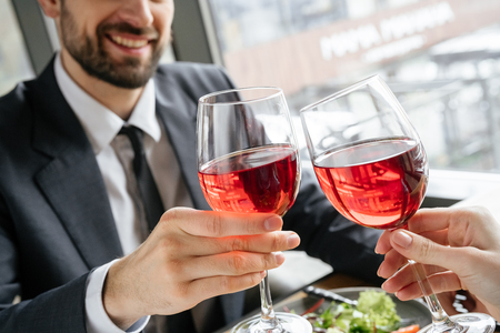 Businesspeople having business lunch at restaurant sitting eating salad drinking wine cheers glasses close-upの写真素材