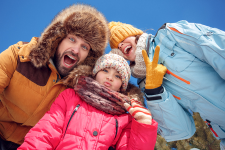Winter vacation. Family time together outdoors grimacing to camera laughing playful bottom view close-upの写真素材