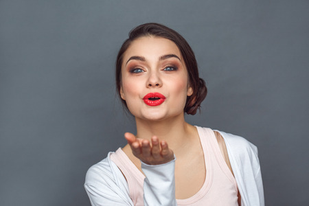 Freestyle. Woman standing isolated on grey sending kiss to camera excited close-upの写真素材