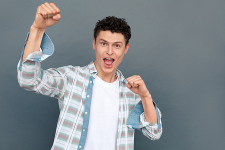 Man isolated on gray wall free style looking camera shouting excited fists upの写真素材