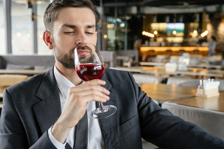 Businessperson on business lunch at restaurant sitting smelling wine joyfulの写真素材