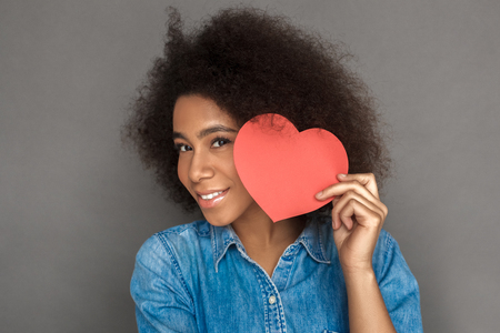 Freestyle. Mulatto woman standing isolated on grey with valentine smiling cheerful face close-upの写真素材