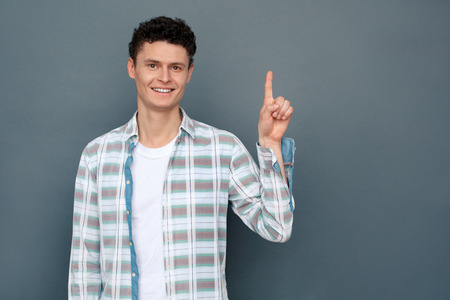 Man isolated on gray wall free style standing pointing up idea looking camera joyfulの写真素材