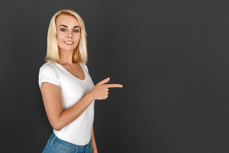 Freestyle. Woman standing isolated on black pointing at wall smiling cheerfulの写真素材