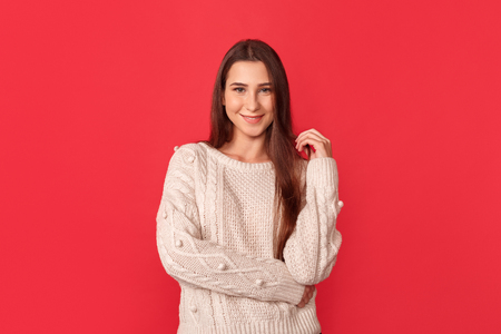 Freestyle. Young woman standing isolated on red posing to camera playfulの写真素材