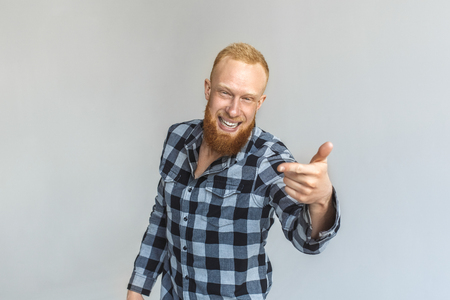 Freestyle. Mature man standing isolated on grey pointing at camera laughing cheerfulの写真素材