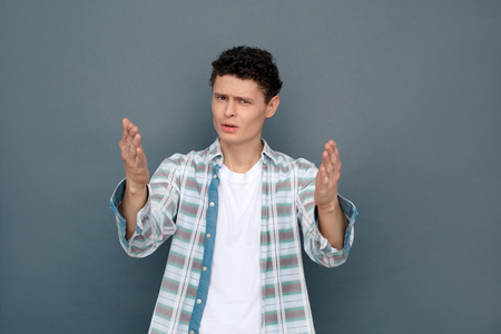 Man isolated on gray wall free style standing looking camera gesturing confused unhappyの写真素材