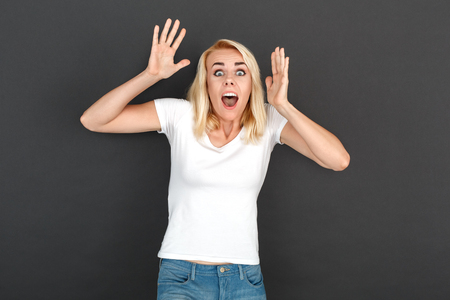 Freestyle. Woman standing isolated on black wall hands up screaming scaredの写真素材