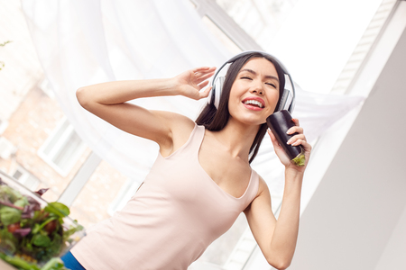 Young girl in headphones at kitchen healthy lifestyle standing singing to eggplant dancing happyの写真素材