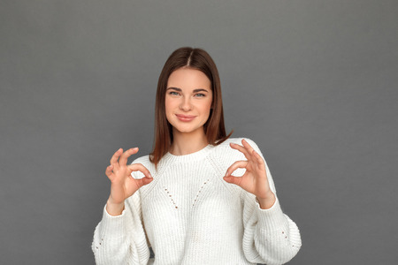 Freestyle. Young girl standing isolated on grey showing ok sign smiling relaxedの写真素材