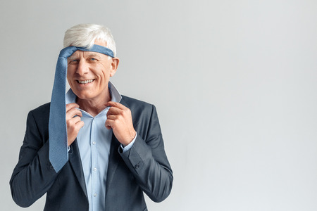 Business Lifestyle. Businessman standing isolated on gray with tie on head laughing sillyの写真素材