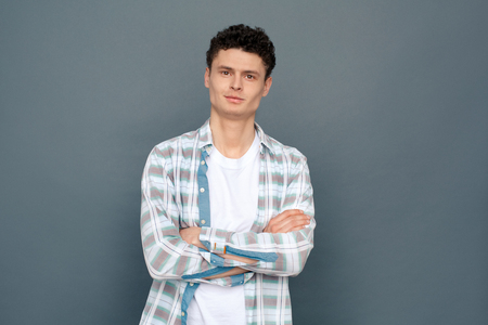 Man isolated on gray wall free style crossed arms looking camera confidentの写真素材
