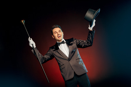 Professional Occupation. Showman in suit standing isolated on wall with hat and cane up smiling excitedの写真素材