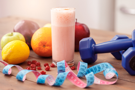 Fruit smoothie dumbbells and tape measure isolated on table healthy lifestyle close-upの写真素材