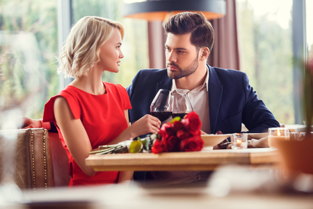 Young couple on date in restaurant sitting cheers with wine glasses looking at each other passionateの写真素材