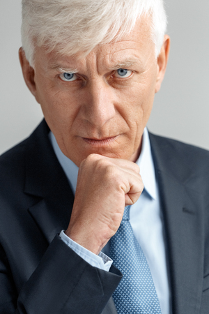 Business Lifestyle. Businessman standing isolated on gray leaning on fist looking camera serious close-upの写真素材