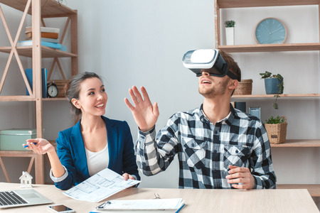 Man at real estate agency sitting in virtual reality headset looking at new house joyfulの写真素材