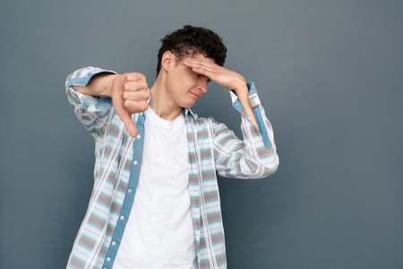 Man isolated on gray wall free style standing covering face thumb down disappointedの写真素材
