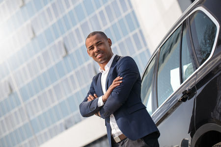 Young man security standing near car crossed arms looking camera cheerful side viewの写真素材