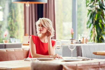 Young woman on date in restaurant sitting looking aside sensualの写真素材