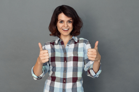 Freestyle. Young woman isolated on grey thumbs up smiling excitedの写真素材
