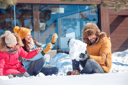 Winter vacation. Family time together outdoors sitting playing with snow laughing cheerfulの写真素材