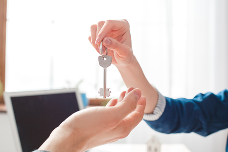 Man at real estate agency sitting agent giving keys to client close-upの写真素材