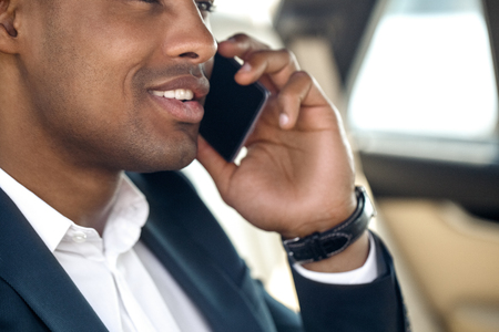 Young businessman sitting in the car talking on smartphone close-up cheerfulの写真素材