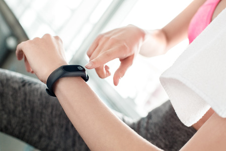 Young girl in gym healthy lifestyle sitting checking information on fitness trackerの写真素材