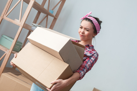 Young girl moving to new place walking carrying heavy box concernedの写真素材