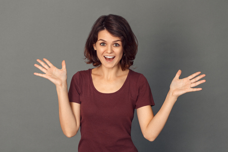 Freestyle. Young woman isolated on grey hands aside laughing cheerfulの写真素材