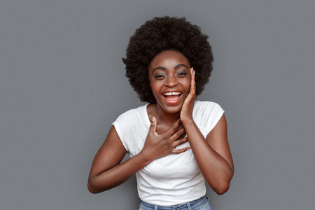 Young woman standing isolated on gray holding face laughing cheerfulの写真素材
