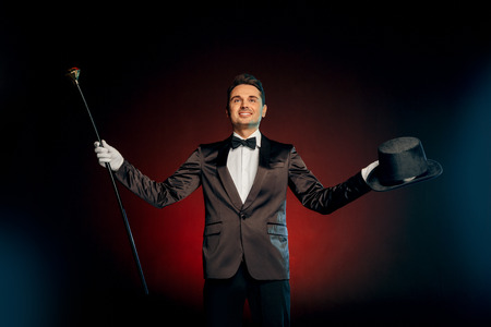 Professional Occupation. Showman in suit standing isolated on wall with hat and cane starting show smiling confidentの写真素材