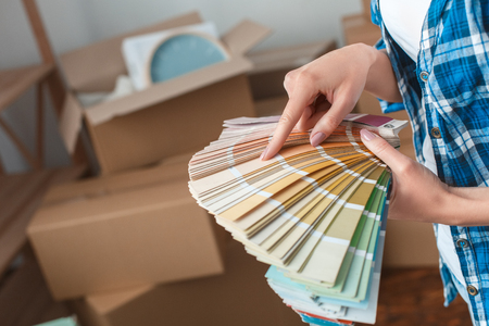 Young woman moving to a new place standing choosing color from palette close-upの写真素材
