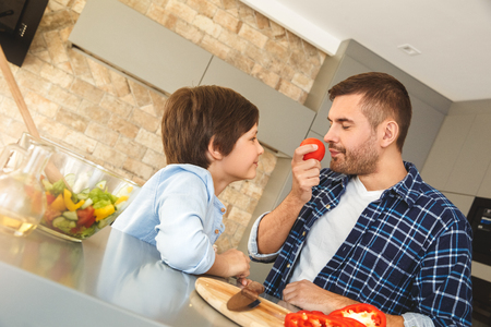 Family at home standing in kitchen together father smelling tomato concentratedの写真素材
