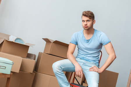 Young man moving to new place sitting grimace playfulの写真素材