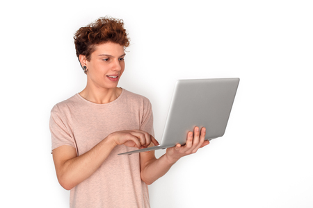 Teenager with earrings studio standing isolated on white browsing laptop joyfulの写真素材