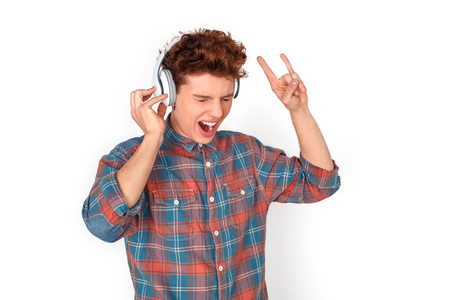 Teenager in headphones studio standing isolated on white listening rock music singingの写真素材
