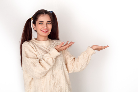 Young girl with two ponytails studio standing isolated on white showing space aside friendlyの写真素材