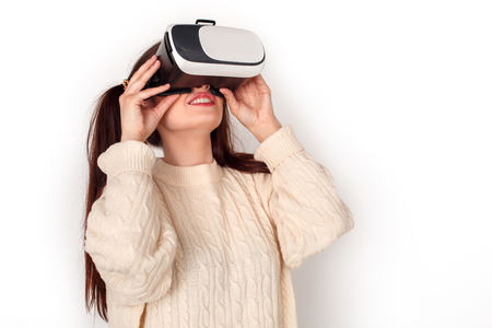 Young girl with two ponytails in virtual reality headset studio standing isolated on white watching video cheerfulの写真素材