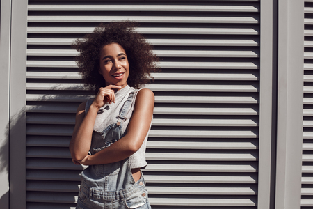 Young woman wearing overall shorts isolated on shutter looking aside cheerfulの写真素材
