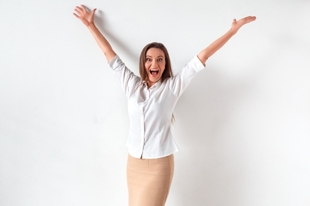 Success achieved. Woman standing isolated on white hands up shouting cheerfulの写真素材