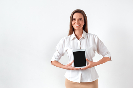 Promotion. Woman standing isolated on white showing screen of digital tablet smiling cheerfulの写真素材