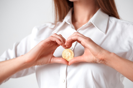 Cryptocurrency. Woman standing isolated on white holding electronic cash in heart shape close-upの写真素材