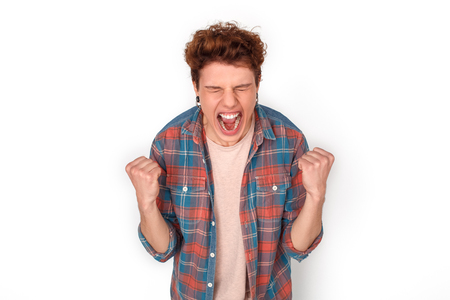Teenager with earrings studio standing isolated on white hands in fist shouting happy close-upの写真素材