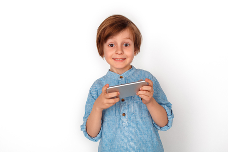 Boy studio standing isolated on grey watching video on smartphone looking camera cheerfulの写真素材