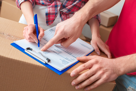 Young girl moving to new place standing with delivery man fulfilling form close-upの写真素材